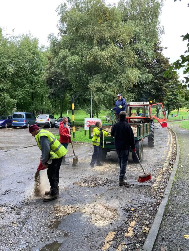Councillors shovelling stone from a trailer onto the track.