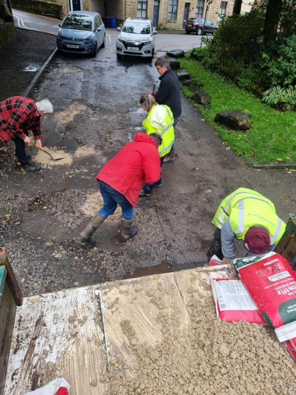 Councillors actively filling the potholes with the stone from the trailer.