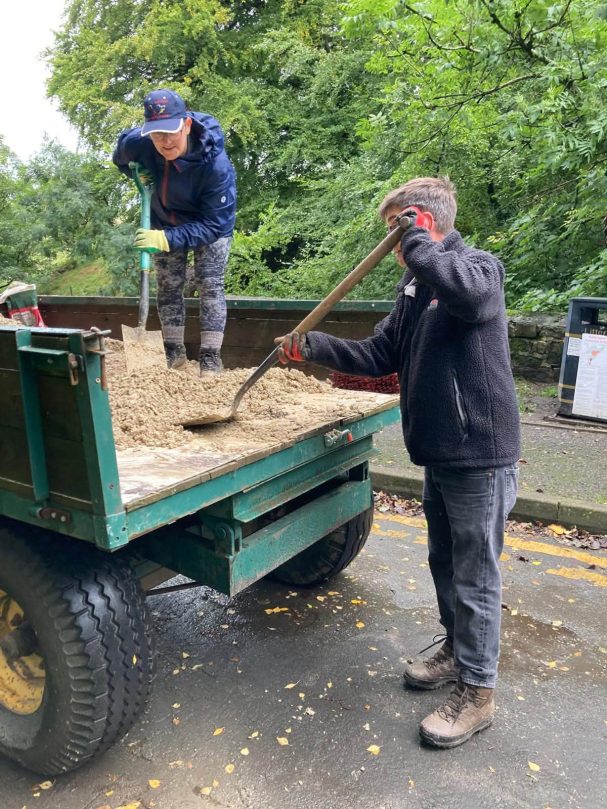 Two Councillors shovelling stone on the trailer.